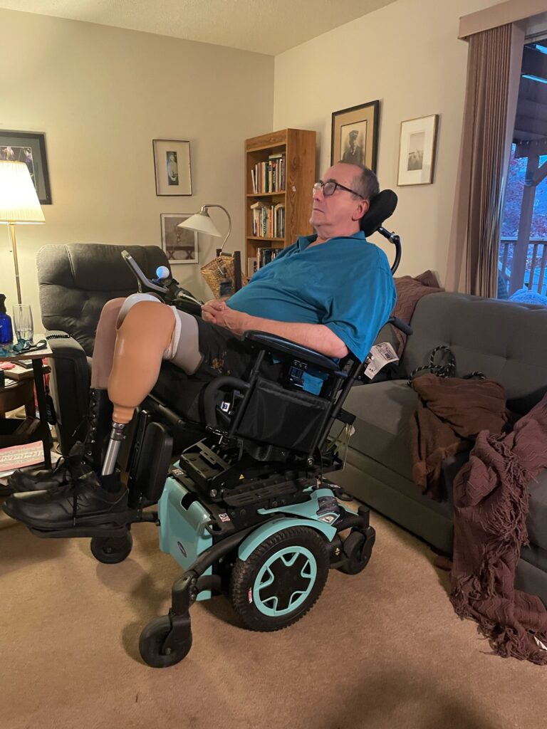 Victor in a power wheelchair that is seafoam colour
